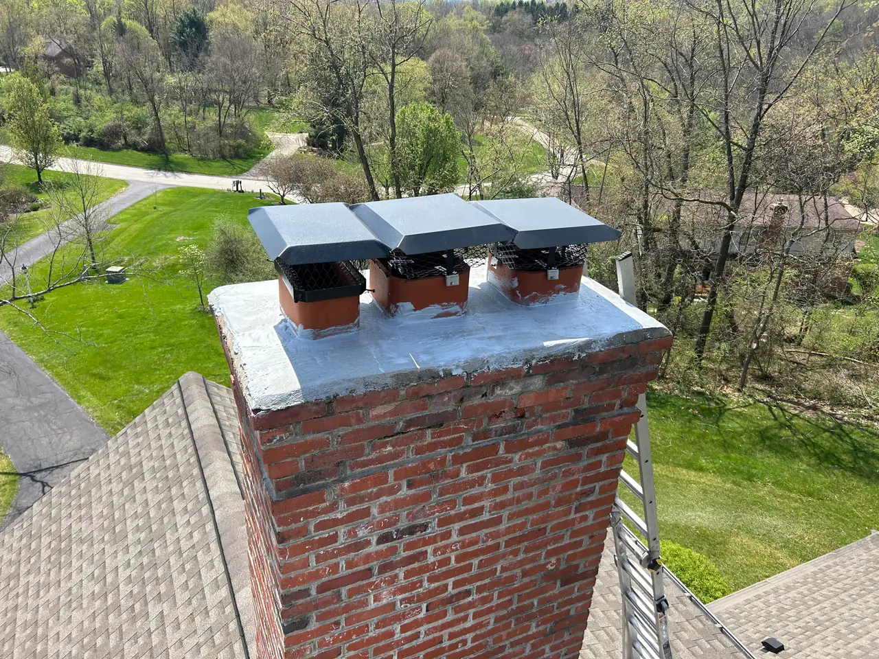 Three black single-flue chimney caps I installed on a red brick chimney with a fresh crown coat in Monroeville, PA