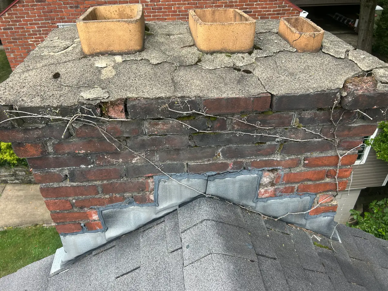 Cracked, spalling crown and deteriorated top brick courses on an older Mt. Lebanon, PA chimney before repair