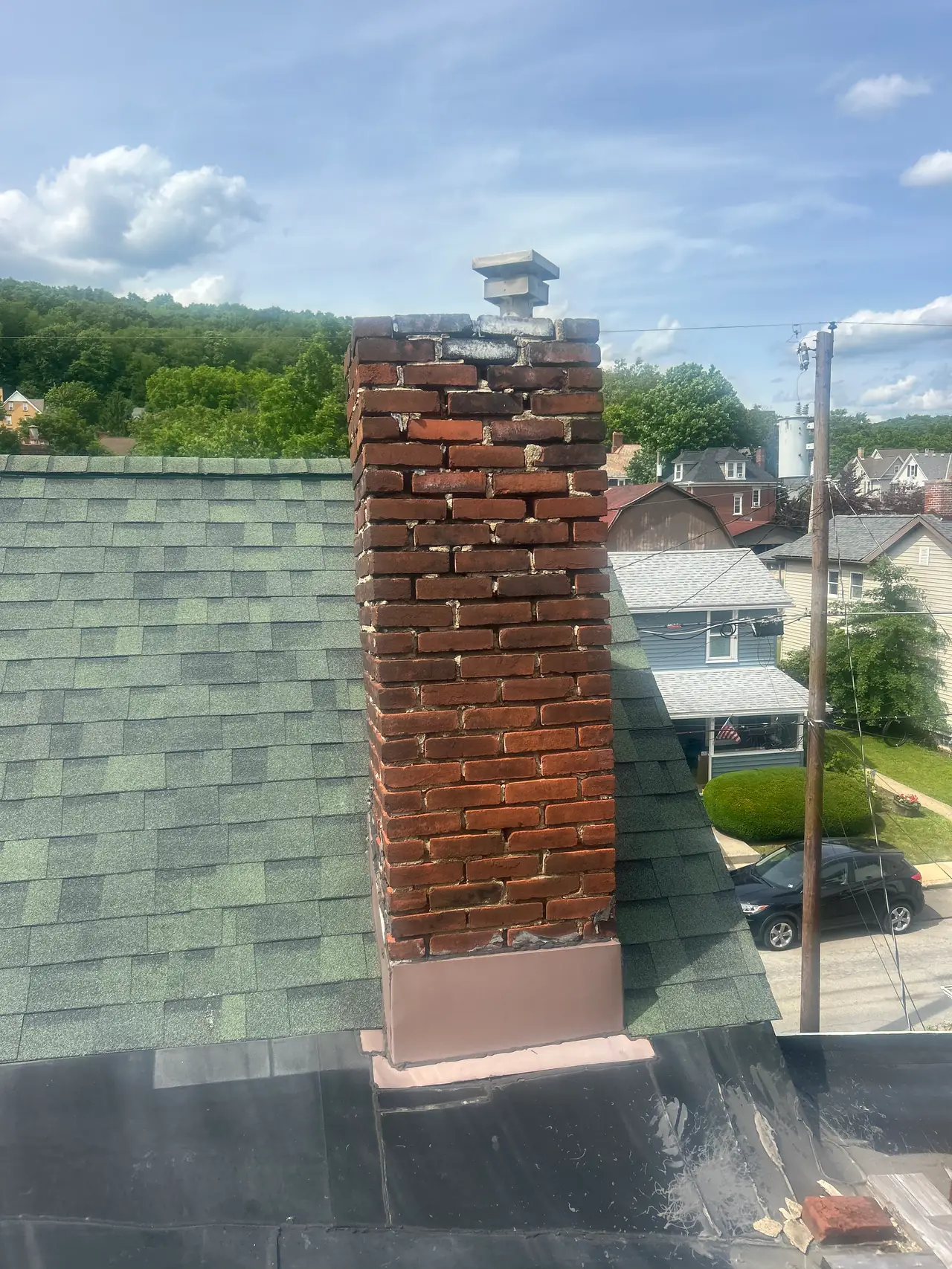 Deteriorated red brick chimney with spalling brick and gapped mortar joints on an older Pittsburgh house, seen during a chimney inspection
