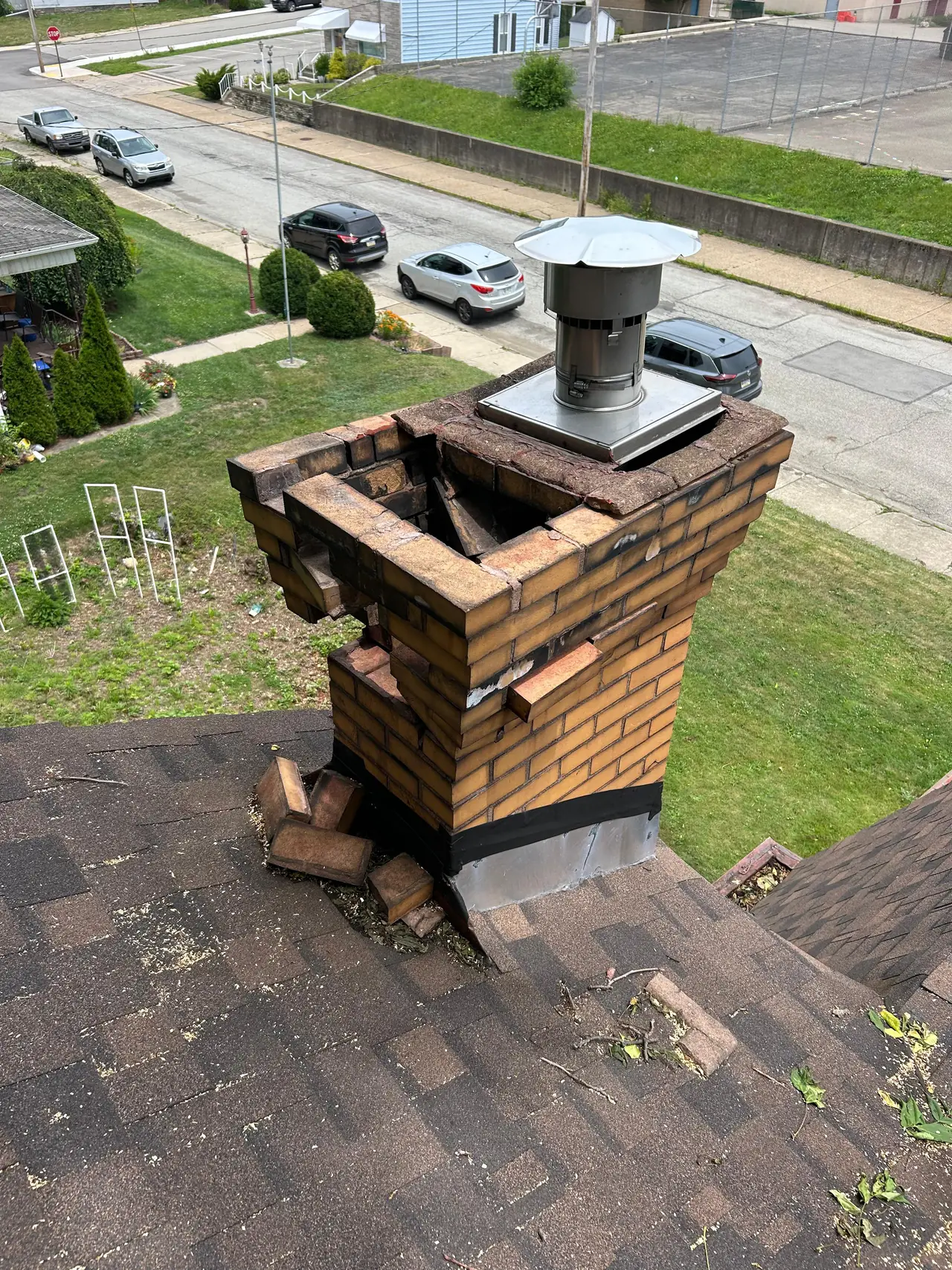 Deteriorated brick chimney with loose and missing bricks before repair in New Kensington, PA