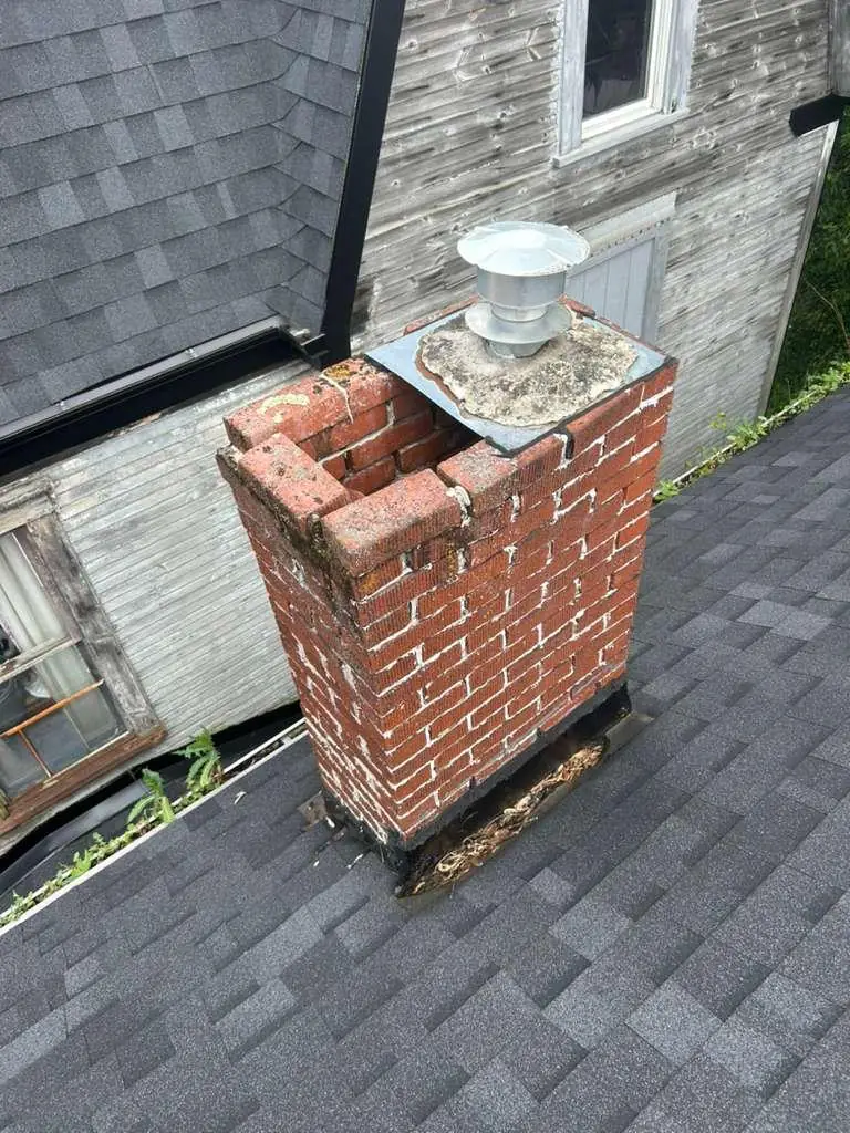 Old red brick chimney with loose top bricks and a cracked crown before repair in Brackenridge, PA