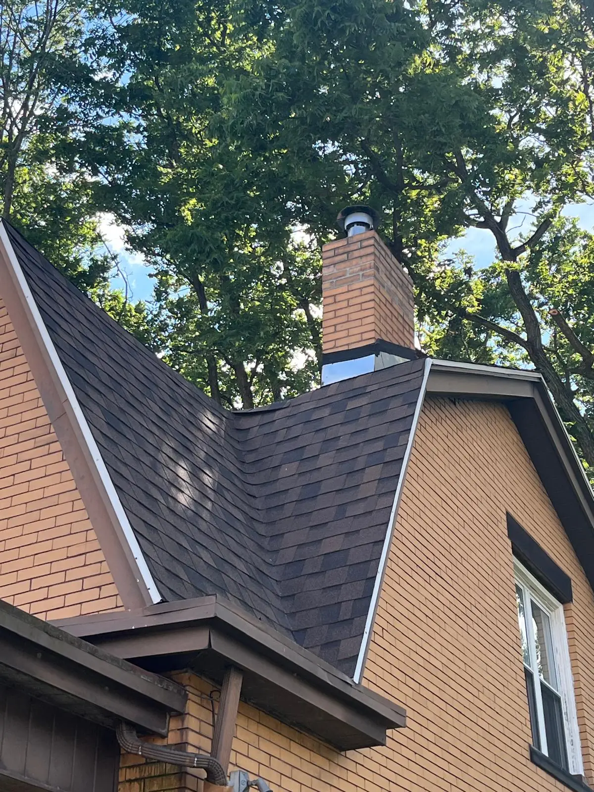 Repaired brick chimney with a new cap standing clean on a New Kensington, PA rooftop