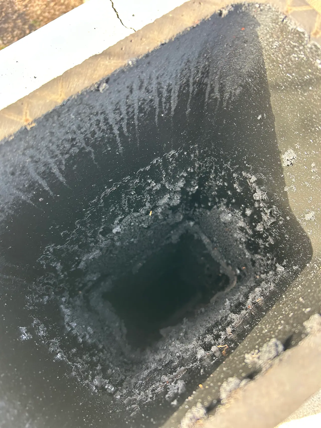Thick, crusty stage two creosote buildup coating the clay tile flue of a Pittsburgh chimney